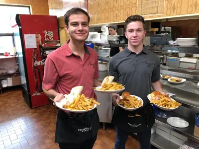 two servers holding food in Haugen's kitchen