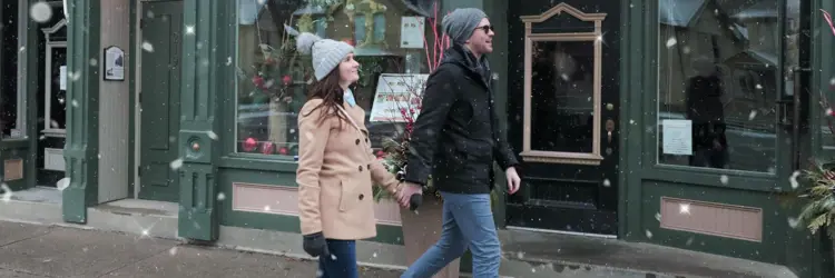 Couple walking down Queen Street exploring stores in light snowfall