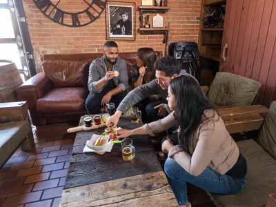 group of friends eating charcuterie and drinking beer in lounge at Old Flame Brewery