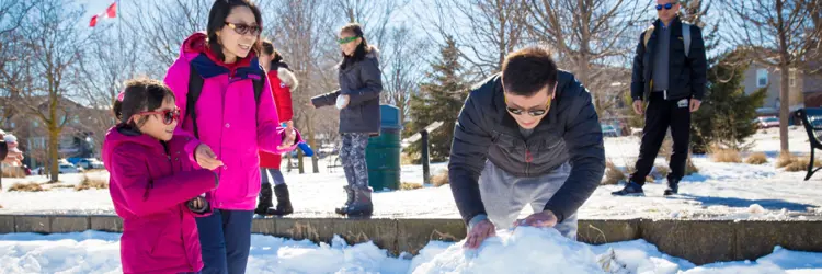 Family building snowman on Lake Scugog shore