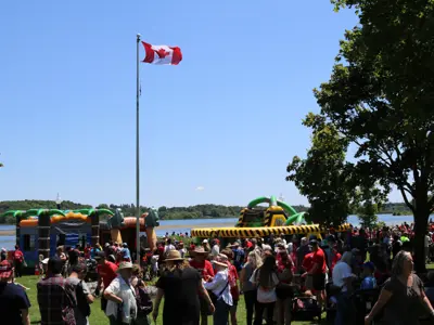 crowd around Canada flag and inflatable play equipment on Canada Day