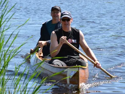 two people in canoe rowing by the shore