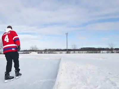 photo from behind of man skating in red hockey jersey